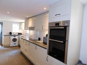 a kitchen with white cabinets and a stove top oven at Chapel Cottage Winton in Kirkby Stephen