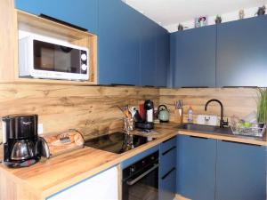 - une cuisine avec des placards bleus et un four micro-ondes dans l'établissement Royan - APPARTEMENT au COEUR du CENTRE-VILLE - PLAGE à SEULEMENT 200m, à Royan