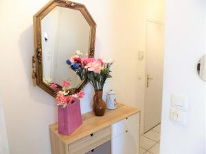un miroir et un vase avec des fleurs sur une commode dans l'établissement Royan - APPARTEMENT au COEUR du CENTRE-VILLE - PLAGE à SEULEMENT 200m, à Royan