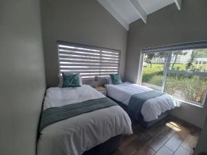 twee bedden in een kamer met een raam bij 22 Oaklands on the Knoll in Knysna
