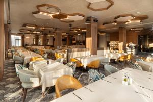 um restaurante com mesas e cadeiras brancas em Atmosphere Balneo Hotel & SPA em Pavel Banya