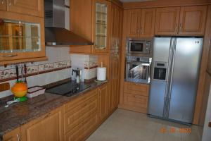 a kitchen with wooden cabinets and a stainless steel refrigerator at Cómoda casa en Cabárceno in Villanueva