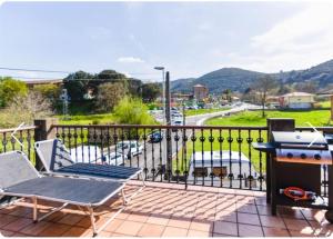 een patio met een grill en stoelen op een balkon bij Cómoda casa en Cabárceno in Villanueva