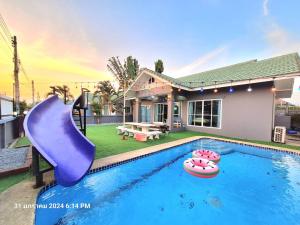 a swimming pool with a purple slide in front of a house at มัลดีฟส์ เวนิซ ไมอามี่ กรีนที หัวหินพูลวิลล่า Maldive Venice Miami Green Tea Hua-Hin Pool Villa in Hua Hin