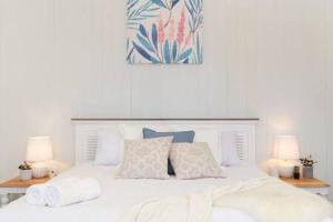 une chambre avec un lit blanc avec des oreillers et deux lampes dans l'établissement Pet Friendly Family Home In Brisbane - Relocations and Family Stays - Fast Internet - Parking - Netflix, à Brisbane