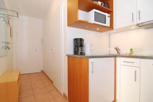 uma cozinha com armários brancos e um micro-ondas em Belvedere, Whg 8 em Westerland
