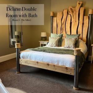 a bedroom with a bed with a wooden headboard at The Roost in Cullompton