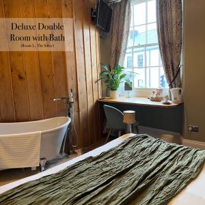 a room with a bed and a tub and a window at The Roost in Cullompton