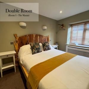 a bedroom with a large bed with a wooden headboard at The Roost in Cullompton
