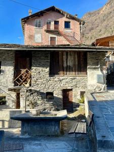 une maison en pierre avec un banc devant elle dans l'établissement Il nido di Curlo, à Chiesa in Valmalenco