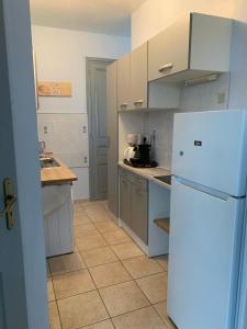 a kitchen with a white refrigerator and a tile floor at L'Ermitage in Pornic