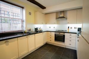 a kitchen with white cabinets and a window at The Bakehouse - central townhouse sleeps 8 people in Winchester