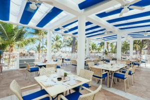 un restaurante con mesas y sillas blancas y palmeras en Bahia Principe Fantasia Punta Cana - All Inclusive, en Punta Cana
