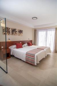 a bedroom with a large bed with white sheets and red pillows at Apartamentos Vista Sur in Playa de las Americas