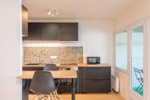 uma cozinha com uma mesa de madeira e cadeiras em Spacious apartment with balcony and parking em La Madeleine