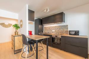 cocina con armarios negros y mesa de madera en Spacious apartment with balcony and parking, en La Madeleine