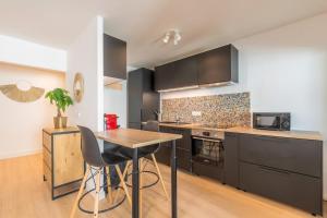 a kitchen with black cabinets and a wooden table at Spacious apartment with balcony and parking in La Madeleine