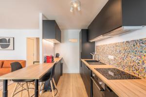 uma cozinha com armários pretos e um balcão de madeira em Spacious apartment with balcony and parking em La Madeleine