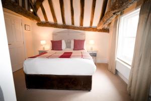 a bedroom with a bed with white sheets and red pillows at The Bakehouse - central townhouse sleeps 8 people in Winchester