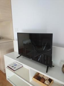 TV de pantalla plana en un centro de entretenimiento blanco en Apartamentos La Pergola Castellón, en Castellón de la Plana