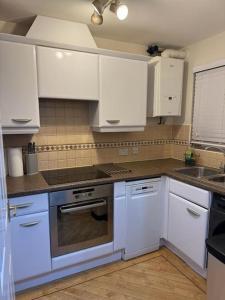 a kitchen with white cabinets and a stove top oven at Greatmindz abode in Kingshurst