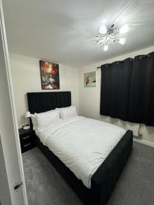 a bedroom with a large white bed with a ceiling fan at Greatmindz abode in Kingshurst