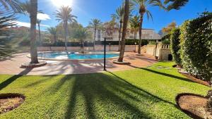 une piscine bordée de palmiers dans une cour dans l'établissement Precioso apartamento en la playa de Jávea By El Conserje, à Jávea 7 autres photos