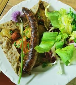 un plato de comida con salchicha y ensalada en Chambres d'Hôtes La Terrasse d'Argein, en Argein