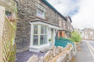 a stone house with a green door on a street at Stylish, family friendly central Windermere home with wood burner in Windermere