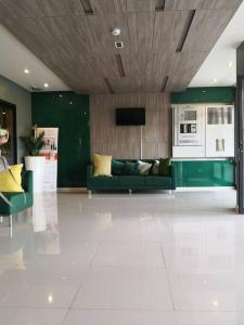 a living room with a green couch and a kitchen at I Condo Suvarnabhumi Airport in Bangkok