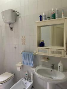 een badkamer met een wastafel, een toilet en een spiegel bij Villa Kenia Flora in Maratea