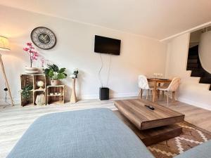 Una sala de estar con una mesa y un televisor en la pared. en Drouet d'Erlon duplex spacieux, terrasse au centre, en Reims