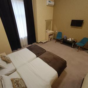 een slaapkamer met een bed, een bureau en een televisie bij Karavan in Yakkasaray