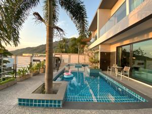 a swimming pool with a palm tree and a house at Twin Villas Seaview Kata in Kata Beach