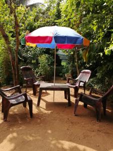 una mesa de picnic con una sombrilla y sillas coloridas en Randeniya Rest inn, en Wellawaya