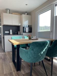 uma cozinha com uma mesa de madeira e cadeiras verdes em Hausboot Heaven on Earth em Klitten