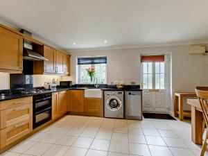 una cucina con armadi in legno, lavatrice e asciugatrice di 3 Bed in Bridgwater 90939 a North Petherton