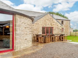 a stone house with a patio with tables and chairs at 8 Bed in Allendale 90713 in Catton