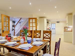 a dining room with a wooden table and a kitchen at 5 Bed in Glastonbury 91657 in Meare