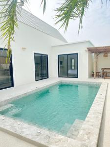 a swimming pool in front of a house at Villa all day Pool Villa Hat Chao Samran หาดเจ้าสำราญ in Haad Chao Samran