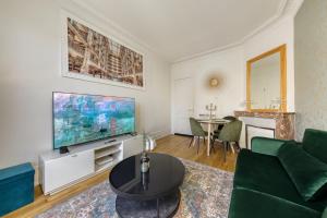 a living room with a green couch and a flat screen tv at -L'émeraude de Louis XVI- Idéal pour Couple-Solo-Pro 8min de Paris-1min de la gare in Enghien-les-Bains