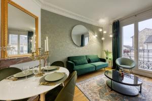 a living room with a table and a green couch at -L'émeraude de Louis XVI- Idéal pour Couple-Solo-Pro 8min de Paris-1min de la gare in Enghien-les-Bains