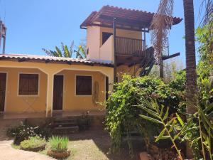 a yellow house with a balcony in a garden at Chalé da Selma I (Isaías) in Alto Paraíso de Goiás