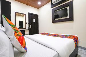 FabExpress Gulshan Grand في مومباي: غرفة نوم مع سرير وتلفزيون على الحائط