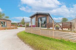 ein winziges Haus mit einem Zaun und zwei Bänken in der Unterkunft Tastefully decorated lodge on popular holiday park, easy access to Lakes and Dales and free parking in Carnforth