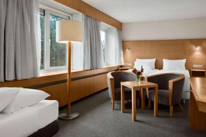 ノールトウェイケルハウトにあるNH ノールトウェイク カンファレンス センター レーウェンホルストのベッド2台、テーブルと椅子が備わるホテルルームです。