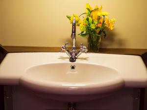 a white sink with a vase of yellow flowers at Segelschiff Weisse Düne in Neppermin