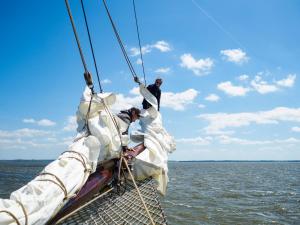 two men on the bow of a sail boat in the water at Segelschiff Weisse Düne in Neppermin