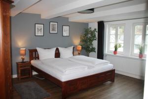 um quarto com uma cama com lençóis brancos e 2 janelas em Ferienhaus Winterberg für 12 Personen Sauna Garten Garage Hund em Winterberg