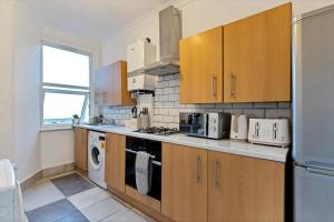 a kitchen with wooden cabinets and a washer and dryer at Stylish 2 Bed Apartment near Central London in London